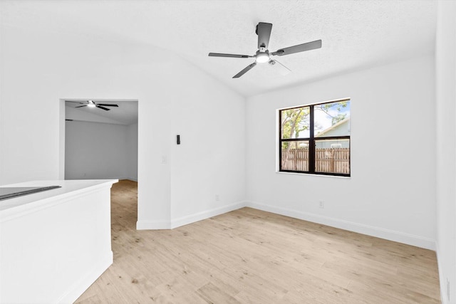 unfurnished room with light wood-type flooring, vaulted ceiling, baseboards, and ceiling fan