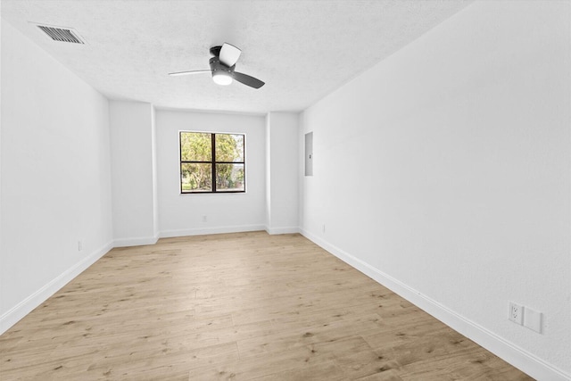 spare room with a textured ceiling, light wood-type flooring, visible vents, and a ceiling fan