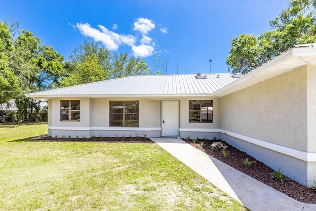 doorway to property with stucco siding, a lawn, and metal roof