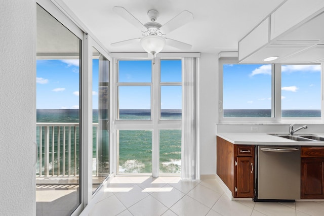kitchen with dishwasher, a sink, a water view, light tile patterned floors, and light countertops