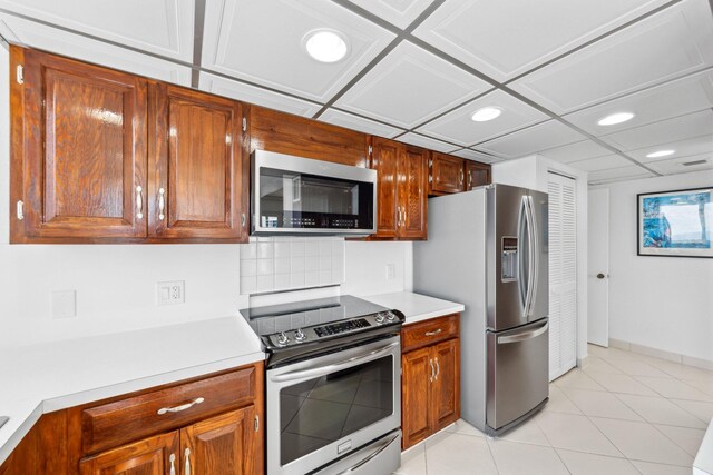 kitchen featuring stainless steel appliances, light countertops, recessed lighting, baseboards, and brown cabinetry