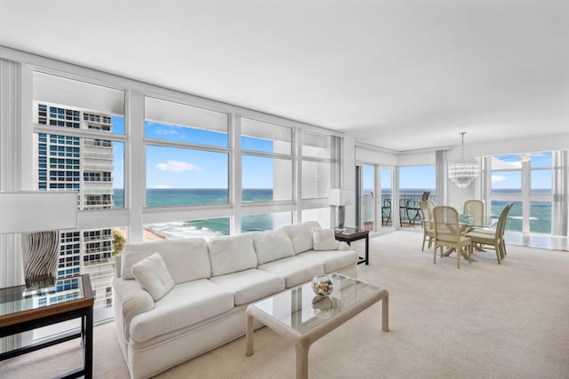 living room featuring a chandelier, a water view, and carpet flooring