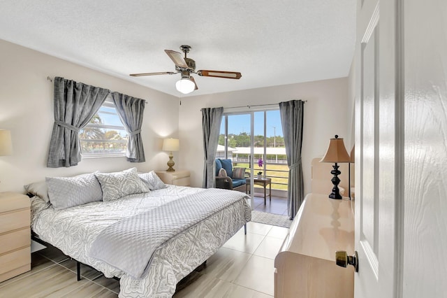 bedroom with a textured ceiling, ceiling fan, and access to exterior