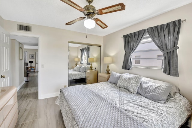 bedroom with visible vents, a closet, ceiling fan, and multiple windows