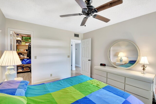 bedroom with visible vents, a ceiling fan, a walk in closet, a closet, and baseboards