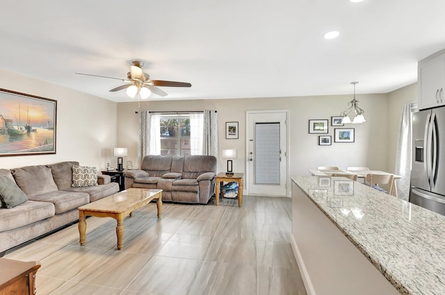 living room featuring a ceiling fan, baseboards, and recessed lighting
