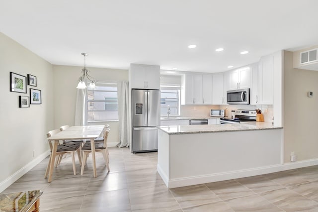 kitchen featuring visible vents, a sink, light stone countertops, a peninsula, and appliances with stainless steel finishes