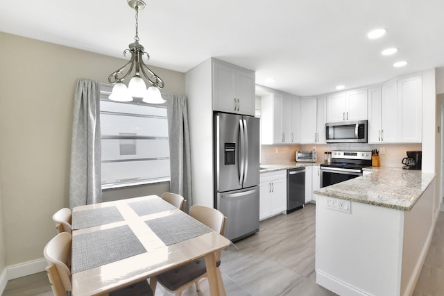 kitchen featuring recessed lighting, stainless steel appliances, light stone countertops, a peninsula, and tasteful backsplash