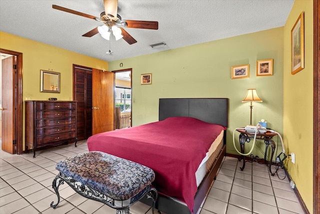 bedroom featuring a textured ceiling, visible vents, baseboards, a closet, and tile patterned floors