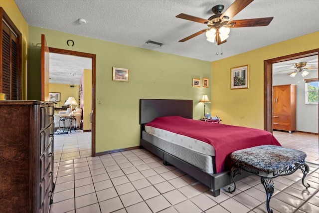 bedroom with light tile patterned floors, a textured ceiling, visible vents, and baseboards