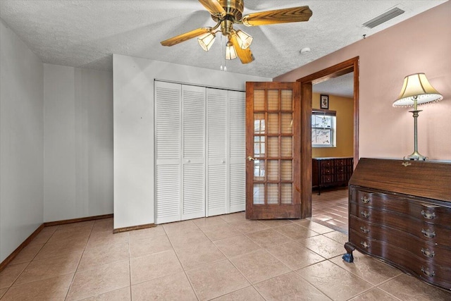 interior space with tile patterned flooring, visible vents, a closet, and a textured ceiling