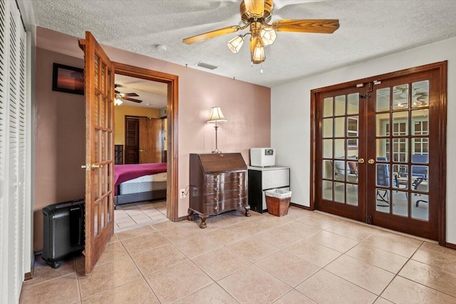 interior space featuring a textured ceiling, ceiling fan, visible vents, french doors, and tile patterned flooring