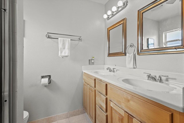 full bathroom with toilet, double vanity, a sink, and tile patterned floors