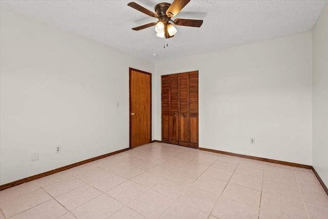 spare room featuring a textured ceiling, ceiling fan, and baseboards