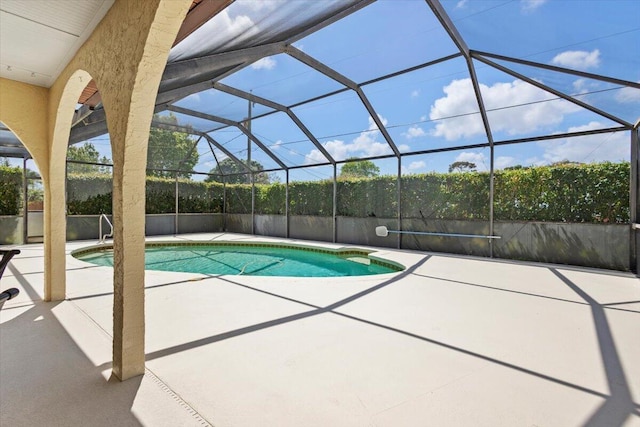 outdoor pool featuring glass enclosure and a patio area