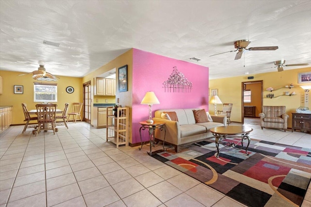 living room with baseboards, visible vents, light tile patterned floors, and ceiling fan