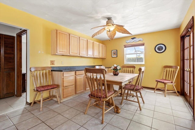 dining area with light tile patterned floors, a ceiling fan, and baseboards