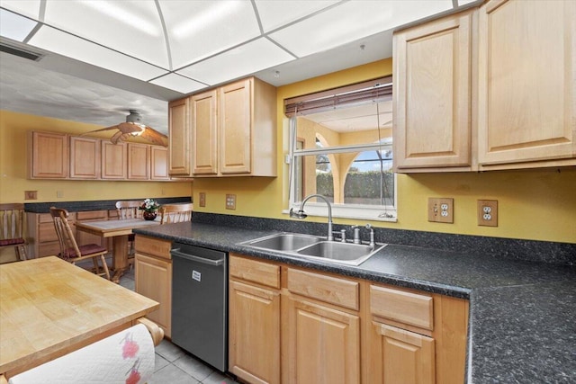 kitchen with dark countertops, light brown cabinets, dishwasher, and a sink