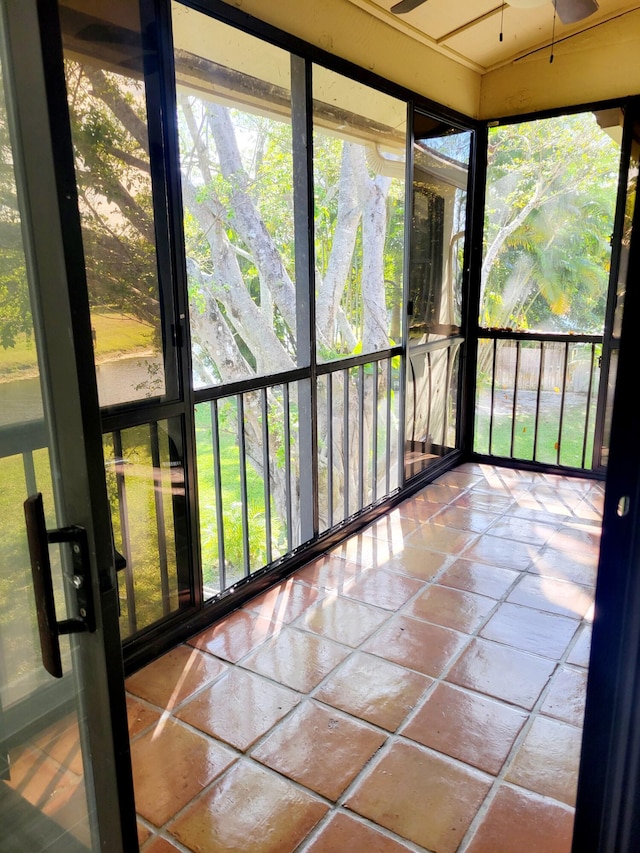 unfurnished sunroom featuring a ceiling fan and a wealth of natural light
