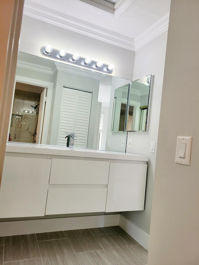 bathroom with baseboards, ornamental molding, a shower, and vanity