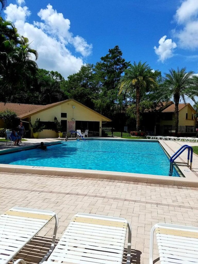 community pool with a patio and fence