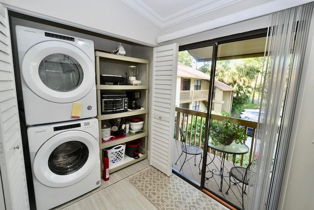clothes washing area with crown molding, stacked washer / drying machine, and laundry area