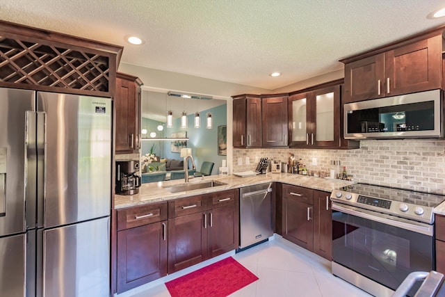 kitchen with backsplash, light stone countertops, stainless steel appliances, and a sink