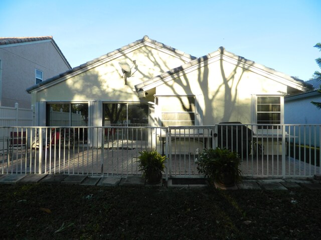 rear view of house featuring stucco siding and fence