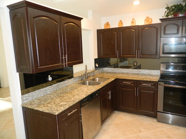 kitchen with light stone counters, a sink, dark brown cabinets, and stainless steel appliances