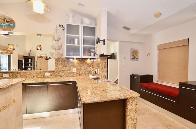 283 NE Sagamore Terrace, Port Saint Lucie, FL 34983 - kitchen with tasteful backsplash, light stone countertops, vaulted ceiling, visible vents, and a peninsula