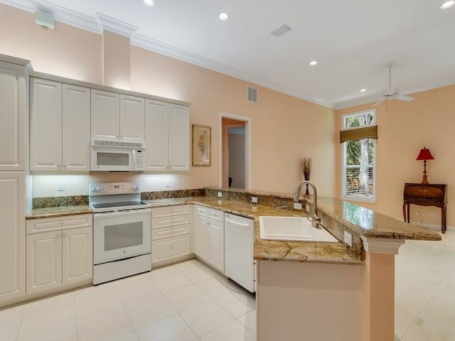 kitchen featuring crown molding, visible vents, a peninsula, white appliances, and a sink