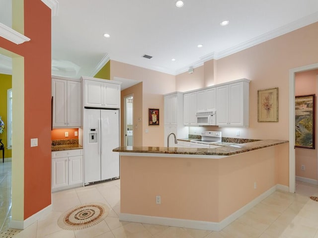 kitchen featuring crown molding, light tile patterned floors, a peninsula, dark stone counters, and white appliances