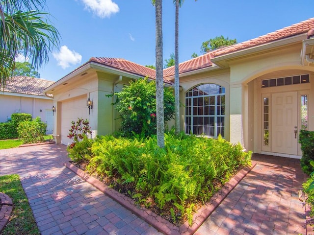 view of front facade featuring an attached garage, stucco siding, a tiled roof, and driveway