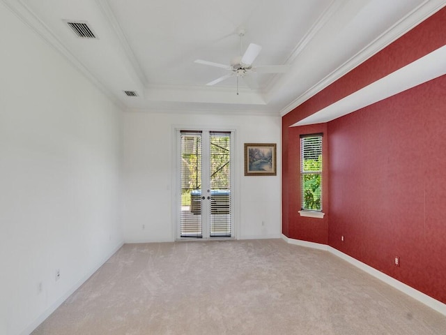 unfurnished room with plenty of natural light, light carpet, a tray ceiling, and visible vents