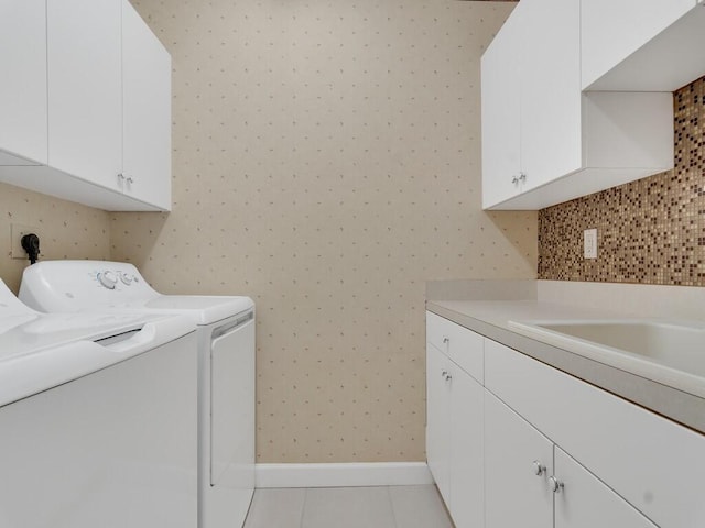 clothes washing area featuring cabinet space, light tile patterned floors, baseboards, wallpapered walls, and washer and clothes dryer