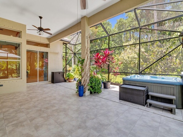 view of patio featuring glass enclosure, a hot tub, and ceiling fan