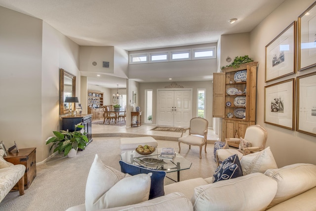 living room with carpet, baseboards, a towering ceiling, a chandelier, and a textured ceiling