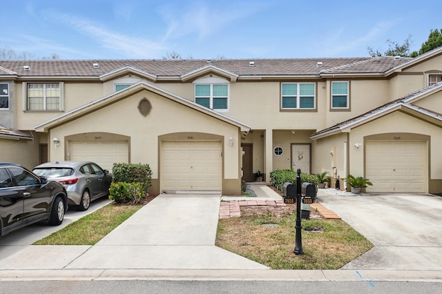multi unit property with stucco siding, an attached garage, and driveway