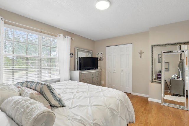 bedroom featuring light wood-type flooring, a closet, and baseboards