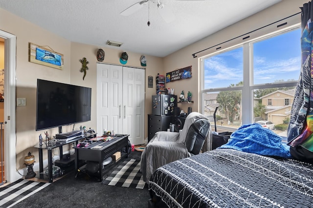 bedroom featuring ceiling fan, a textured ceiling, visible vents, and a closet