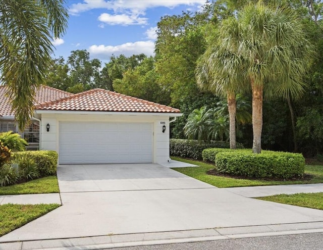 mediterranean / spanish home with stucco siding, driveway, a tiled roof, and an attached garage