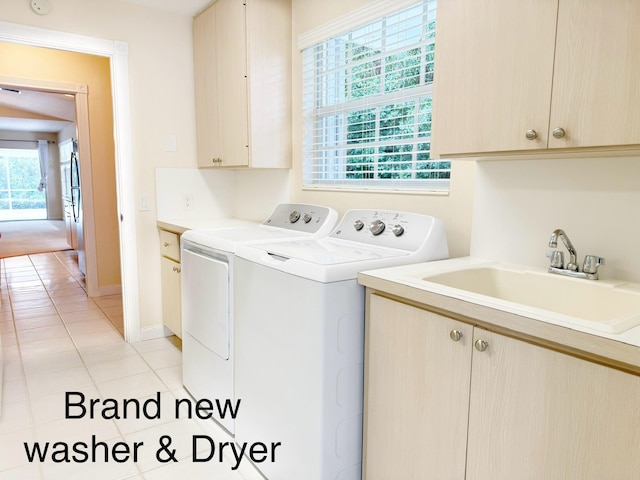 8365 SE Double Tree Dr, Hobe Sound, FL 33455 - laundry area featuring washing machine and clothes dryer, cabinet space, light tile patterned floors, and healthy amount of natural light