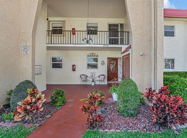 176 Lake Carol Dr, West Palm Beach, FL 33411 - entrance to property featuring covered porch, a balcony, and stucco siding