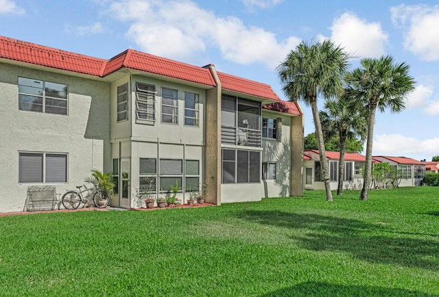176 Lake Carol Dr, West Palm Beach, FL 33411 - rear view of property featuring a yard, a tiled roof, and stucco siding