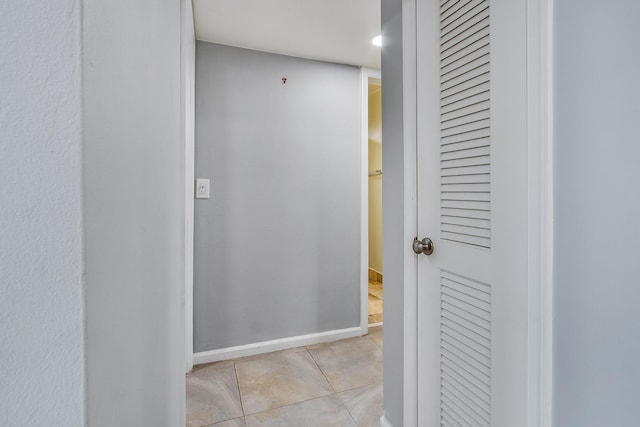 corridor featuring baseboards and light tile patterned floors
