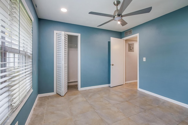 unfurnished bedroom with a closet, light tile patterned flooring, electric panel, baseboards, and visible vents