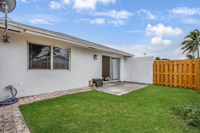 rear view of house featuring fence, a lawn, a patio, and stucco siding