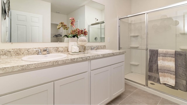bathroom featuring tile patterned floors, a sink, a shower stall, and double vanity