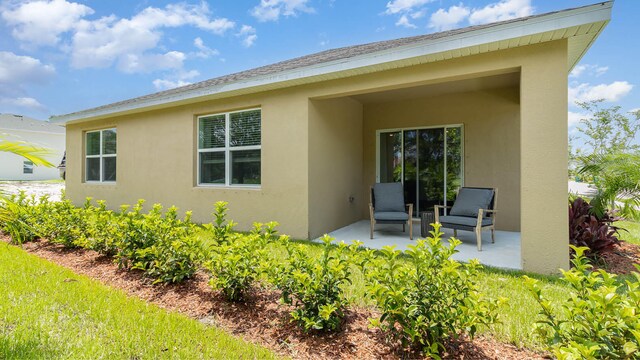 rear view of property with a patio area and stucco siding