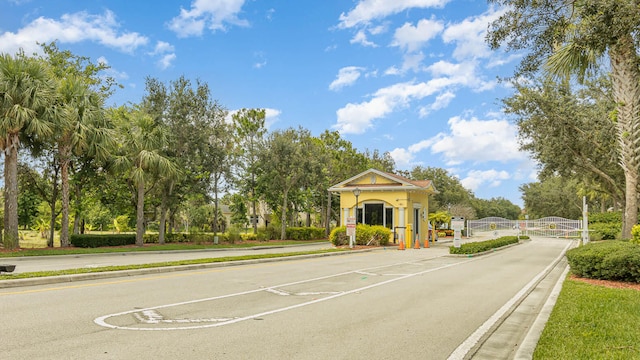 view of road with a gated entry, curbs, a gate, and sidewalks
